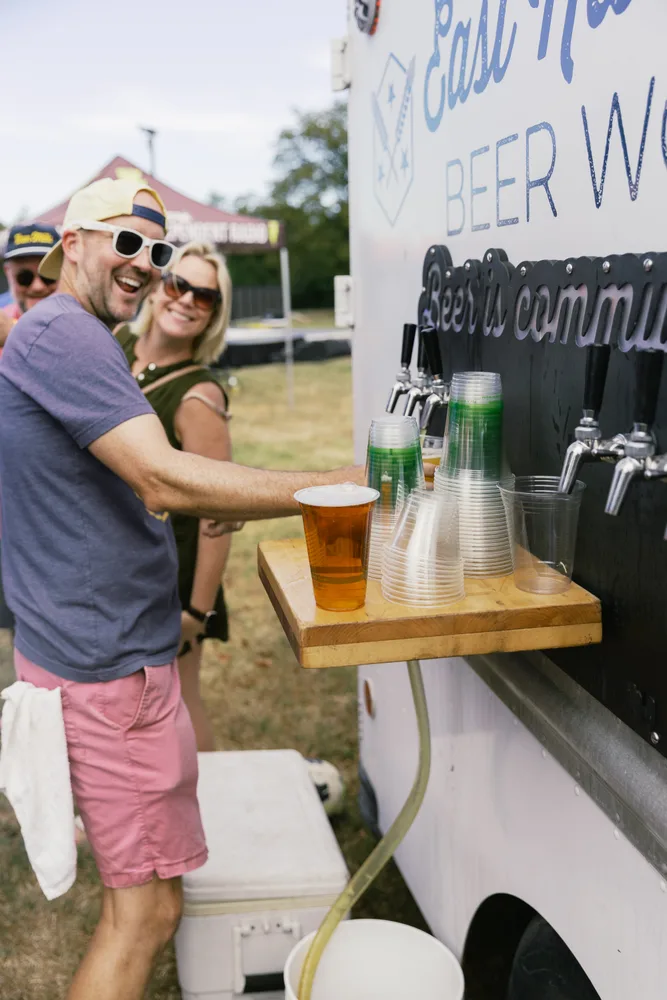 Smiling festivalgoers beside the East Nashville Beer Works taps.