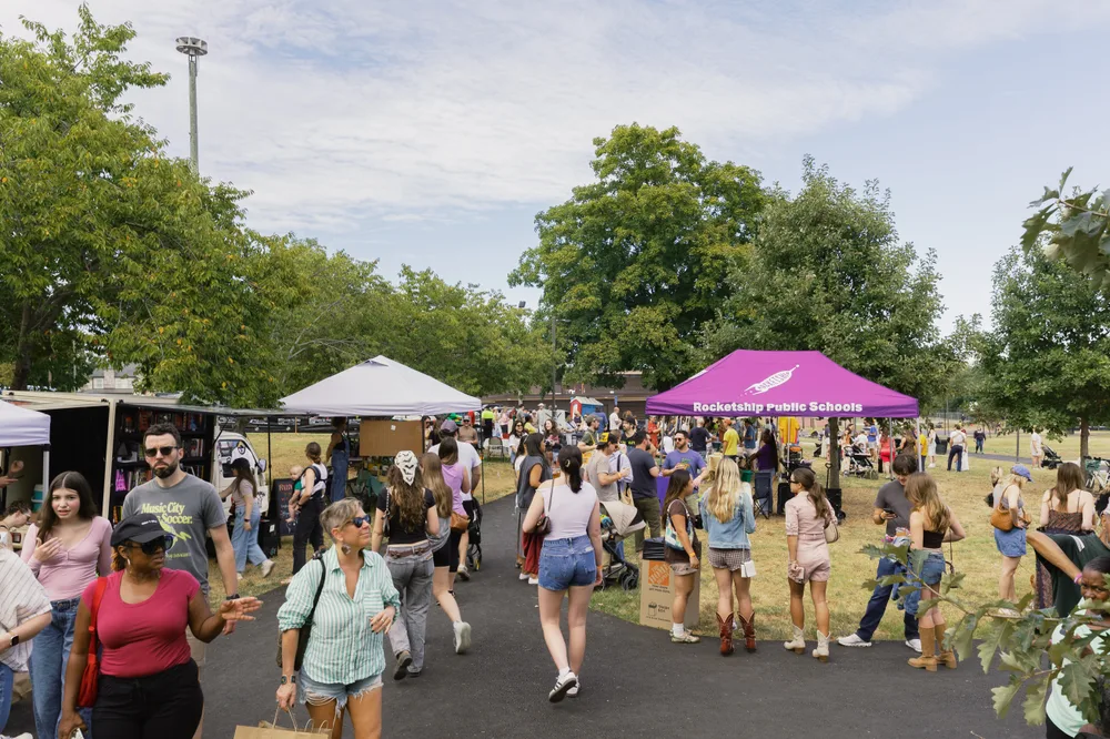 Neighbors exploring the vendor tents along the park path at Fall Fest.